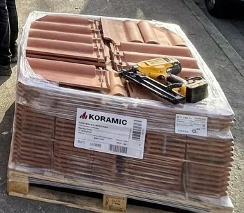 Palette de tuiles neuves et cloueur posés sur le trottoir avant la pose, chantier de couverture à Toulouse